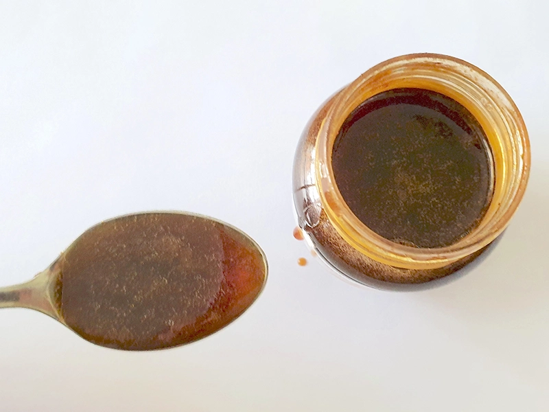 A small, single teaspoon serving of mad honey, illustrating the recommended safe dosage for a first-time tasting experience in Nepal.