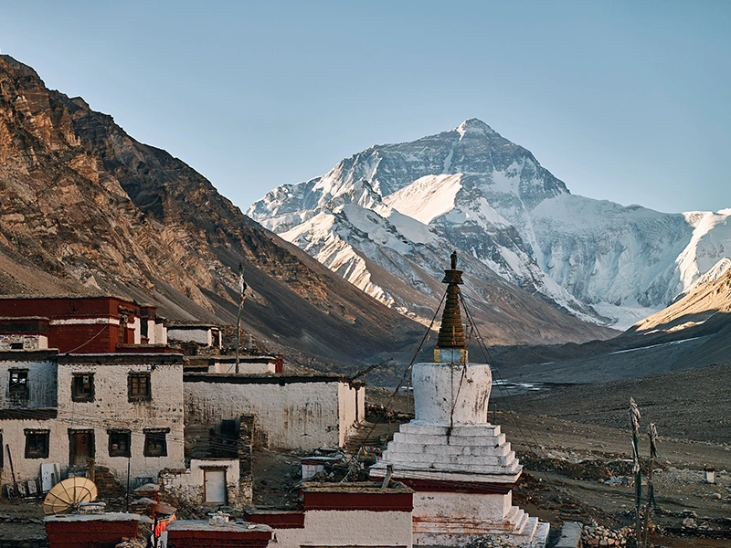 standing on the south side of Rongbuk Monastery, you can overlook Mount Everest, which appears like a colossal pyramid rising among the surrounding peaks, evoking a sense of its vastness and grandeur